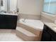 Bathroom featuring a corner soaking tub with tile surround and a granite vanity at 4624 Via Veneto Ct, Kissimmee, FL 34746
