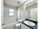 Bright bathroom featuring a shower-tub combo, a large mirror, and a stylish vanity with a blue countertop at 468 Rio Grande Ct, Kissimmee, FL 34759