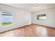 Bright bedroom featuring wood-look floors and two windows, creating an airy and inviting space at 478 Chicago Woods Cir, Orlando, FL 32824