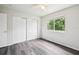 A bright bedroom featuring hardwood floors, ceiling fan, and a window with a view of lush greenery at 478 Chicago Woods Cir, Orlando, FL 32824