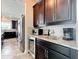Wet bar featuring granite counters, dark cabinetry, and stainless steel refrigerator at 4993 Southlawn Ave, Orlando, FL 32811