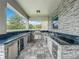 Outdoor kitchen featuring built-in BBQ, mini refrigerator, and granite counters by stone pillar at 4993 Southlawn Ave, Orlando, FL 32811