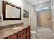 Bathroom with granite counters, framed mirror and tub with shower at 5018 Tupelo Ct, Minneola, FL 34715