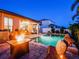 Backyard at night with a sparkling pool and an inviting fire pit, creating a cozy and relaxing outdoor atmosphere at 5018 Tupelo Ct, Minneola, FL 34715