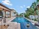 Relaxing backyard with a sparkling pool, elegant stone patio, and tropical landscaping, perfect for outdoor enjoyment at 5018 Tupelo Ct, Minneola, FL 34715