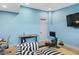 Light blue flex room featuring a workout machine, a desk, and a striped black and white chair with light hardwood floors at 507 S Pine St, New Smyrna Beach, FL 32169