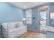 Light blue bedroom featuring a white bed, a window and an exterior door that leads to a porch with a white rocking chair at 507 S Pine St, New Smyrna Beach, FL 32169
