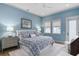 Comfortable bedroom with a patterned bedspread, soft lighting, and tranquil blue walls at 507 S Pine St, New Smyrna Beach, FL 32169
