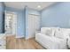 Light blue bedroom features a white bed, closet and a doorway that leads to a bathroom with a tiled floor and a shower at 507 S Pine St, New Smyrna Beach, FL 32169