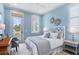 Light blue bedroom with white headboard, gray accents, and natural light from windows and door leading to outdoor porch at 507 S Pine St, New Smyrna Beach, FL 32169