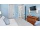 Light blue bedroom with white bedding, dresser, and open door to an attached bathroom with white tile at 507 S Pine St, New Smyrna Beach, FL 32169
