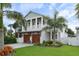Charming two-story home with a well-maintained lawn and elegant garage doors, complemented by lush palm trees at 507 S Pine St, New Smyrna Beach, FL 32169
