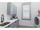 Functional laundry room with gray cabinets, quartz countertop, and modern appliances at 507 S Pine St, New Smyrna Beach, FL 32169
