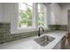 Charming kitchen featuring a stainless steel sink, green subway tile backsplash, and large windows for natural light at 622 S Ingraham Ave, Lakeland, FL 33801