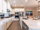 Modern kitchen with white cabinets, quartz countertops, stainless steel appliances, and an open layout to the dining area at 7951 Haverhill Way, Kissimmee, FL 34747