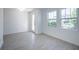 A bright living room with light gray wood-look floors, white walls and baseboards, windows and door at 9199 Waverly Walk Dr, Orlando, FL 32817