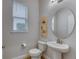 Well-lit powder room featuring a pedestal sink, modern fixtures, and a stylish round mirror at 9422 Jaywood Rd, Winter Garden, FL 34787