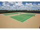 Two tennis courts offer a vibrant green surface with white lines, surrounded by high fences and lush greenery at 9422 Jaywood Rd, Winter Garden, FL 34787
