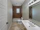 Bathroom with a tiled shower/tub combo, travertine flooring, and a white sink at 10170 Se 106Th Ln, Belleview, FL 34420