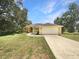 Charming yellow home featuring a spacious front yard, attached two-car garage, and meticulously landscaped entry at 10170 Se 106Th Ln, Belleview, FL 34420
