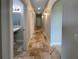 Hallway with travertine flooring leading to a bathroom and other rooms, illuminated by sconce lighting at 10170 Se 106Th Ln, Belleview, FL 34420