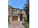 Townhome showcasing a one car garage, brick paved driveway, and well-manicured lawn at 11187 Savannah Landing Cir, Orlando, FL 32832