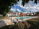 Community pool view with palm trees, red umbrellas, and plenty of lounge chairs for relaxing in the sun at 11568 Westwood Blvd # 1015, Orlando, FL 32821