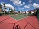 A fenced in tennis court with net and pink and green playing surface near the buildings at 11568 Westwood Blvd # 1015, Orlando, FL 32821