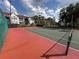 A fenced in tennis court with net and pink and green playing surface near the buildings at 11568 Westwood Blvd # 1015, Orlando, FL 32821