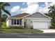 Inviting single-Gathering home featuring a two-car garage, stone accents, and lush landscaping at 1207 Normandy Dr, Haines City, FL 33844