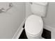 Close-up of white toilet and brushed nickel paper holder with black and white tiled floor at 1404 Oak Pl # A, Apopka, FL 32712