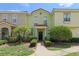 Charming two-story townhome with colorful exterior, featuring tiled roof, manicured lawn, and walkway to the front door at 214 Monroe Cir, Davenport, FL 33896