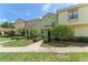 Charming townhome with red tiled roof, mature landscaping, and inviting walkway on a sunny day at 214 Monroe Cir, Davenport, FL 33896