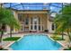 Back exterior of home featuring an enclosed in-ground pool, manicured landscaping, and brick patio at 2357 Alaqua Dr, Longwood, FL 32779