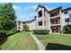 Multi-story condo building with a red tile roof, a grassy lawn, and a sidewalk leading to the front entrance at 3028 Parkway Blvd # 308, Kissimmee, FL 34747