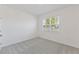 A bright bedroom features neutral carpet, walls and a window overlooking a tree at 3088 Windswept, Wildwood, FL 34785