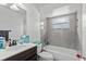 Updated bathroom featuring gray tile, shower-tub combo, and modern fixtures at 310 E Gulley Ave, Oakland, FL 34760