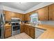 Well-lit kitchen featuring wood cabinetry, laminate countertops, stainless steel appliances, and tile flooring at 310 E Gulley Ave, Oakland, FL 34760