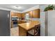 Functional kitchen featuring wood cabinetry, laminate countertops, stainless steel appliances, and tile flooring at 310 E Gulley Ave, Oakland, FL 34760