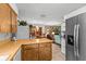 Open kitchen flows to dining area, featuring wooden cabinets and stainless steel refrigerator at 310 E Gulley Ave, Oakland, FL 34760