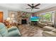 Inviting living room featuring a stone fireplace, wood-look flooring, a comfortable seating arrangement, and natural light at 310 E Gulley Ave, Oakland, FL 34760