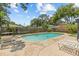 Backyard featuring an in-ground pool, lounge chairs, privacy fence and mature landscaping at 310 E Gulley Ave, Oakland, FL 34760