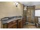 Bathroom featuring unique tile floors, dark vanity, walk-in glass shower, and decorative wall sconces at 4420 Conway Gardens Rd, Orlando, FL 32806