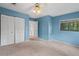 Bedroom features blue walls, ceiling fan, and view of the greenery outdoors at 4420 Conway Gardens Rd, Orlando, FL 32806