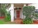 Inviting front entrance featuring a red door, tiled porch, and lush landscaping at 4420 Conway Gardens Rd, Orlando, FL 32806