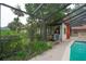 Enclosed pool area with shimmering water and lush greenery, with a cottage-like structure visible through the screen at 4420 Conway Gardens Rd, Orlando, FL 32806