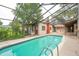 Enclosed pool area with shimmering water, complete with an attached cottage-like structure featuring a vibrant red chimney at 4420 Conway Gardens Rd, Orlando, FL 32806