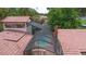 Aerial view of a refreshing screened-in pool surrounded by a red tile roof and mature trees at 4420 Conway Gardens Rd, Orlando, FL 32806