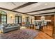 Open-concept living area with terracotta floors, beamed ceilings, and arched windows leading to the kitchen and dining area at 522 Cherokee Dr, Orlando, FL 32801