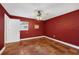 Bedroom with red walls, tile floor, ceiling fan, and natural light from the window at 663 Romano Ave, Orlando, FL 32807